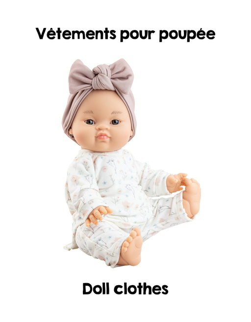 Doll wearing a white outfit with a bow on a white background