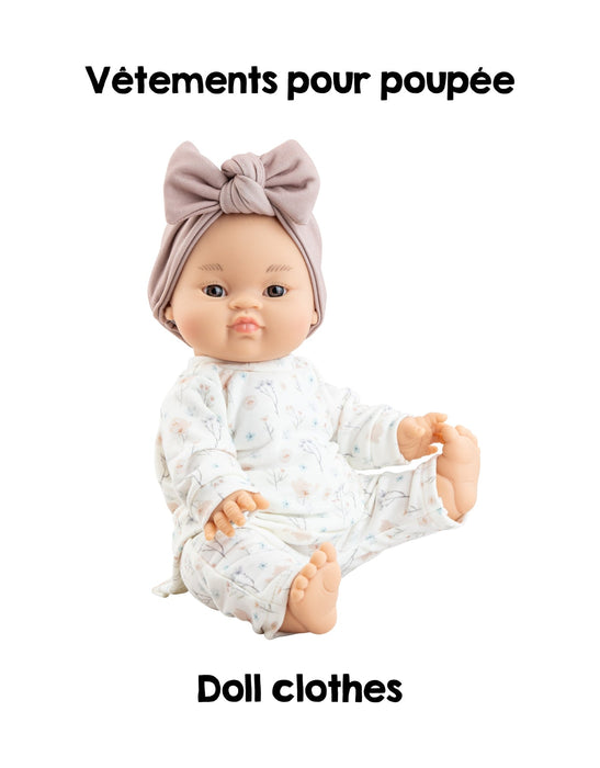 Doll wearing a white outfit with a bow on a white background