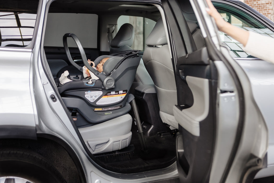 Child in a car seat inside a vehicle with an open door.