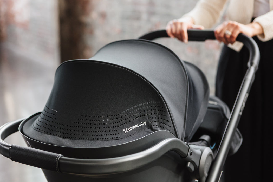 Black stroller with a person holding the handle, blurred background