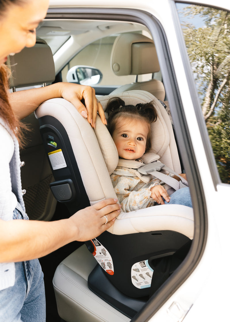 Woman adjusting a car sit fit for a child rear facing inside a vehicle