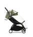 Black stroller with green canopy and clear rain cover on a white background