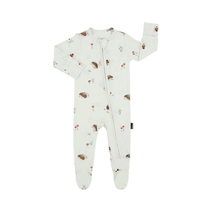 A baby's long-sleeve footed one-piece sleeper in an off-white/cream color, featuring an all-over print of brown hedgehogs, small red mushrooms, and tiny gray birds. The sleeper has a front zipper and is shown flat on a white background.