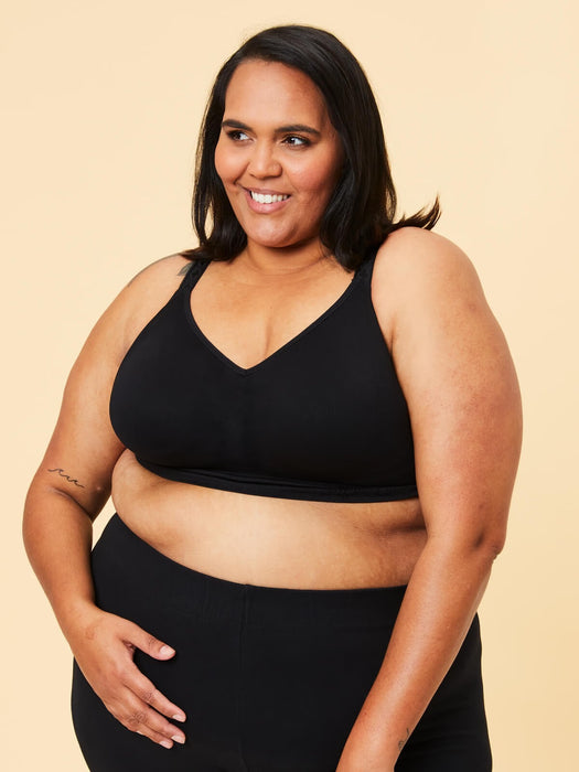 Woman wearing a black Cake bra and leggings on a beige background