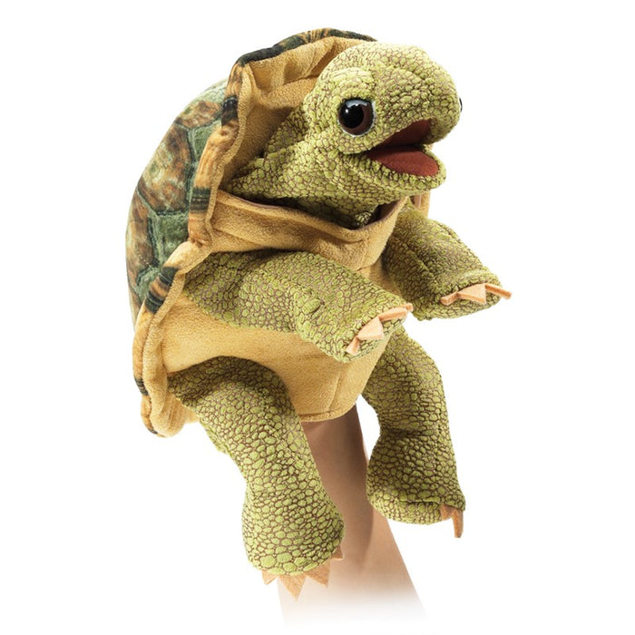 Plush turtle toy on a mannequin arm with a white background