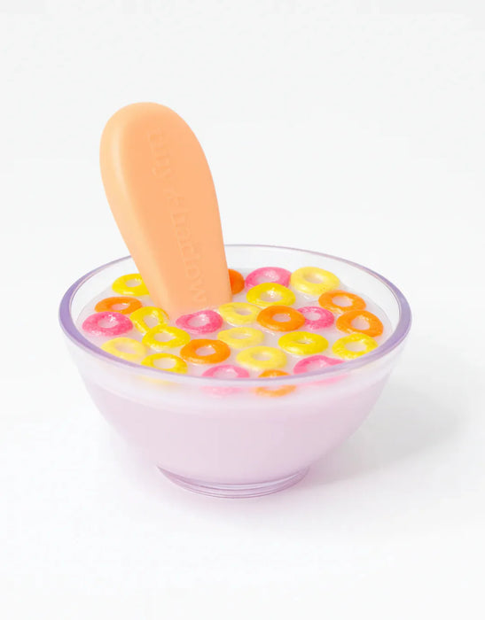 Clear glass bowl with colorful cereal loops and a wooden spoon on a white background