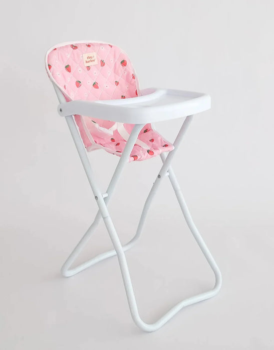 White high chair with a pink cushion featuring red strawberry patterns on a light gray background