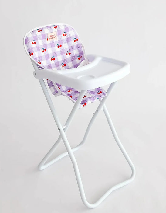 White high chair with a purple checkered cushion featuring red cherries on a light gray background