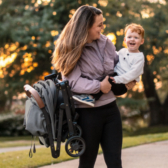 Woman carrying her child on one side and the Minu V2 on the other shoulder demonstrating its light weight capabilities.