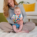 Woman holding a baby with a colorful toy in a cozy living room.