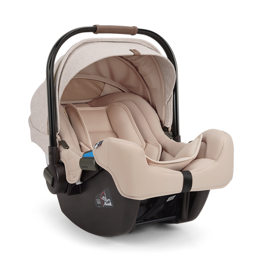 A Nuna baby car seat in a light beige fabric with a black base, shown on a clean white background.