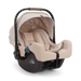A Nuna baby car seat in a light beige fabric with a black base, shown on a clean white background.
