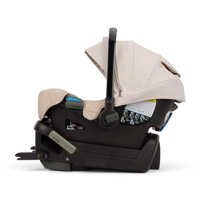 A Nuna baby car seat in a light beige fabric with a black base, shown on a clean white background.