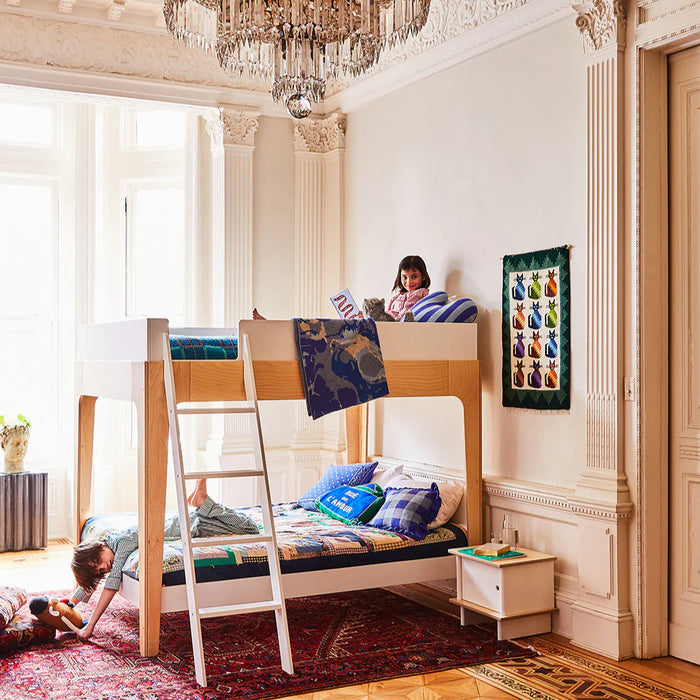 Children playing on a full size Oeuf wooden bunk bed in a stylish room with a chandelier.