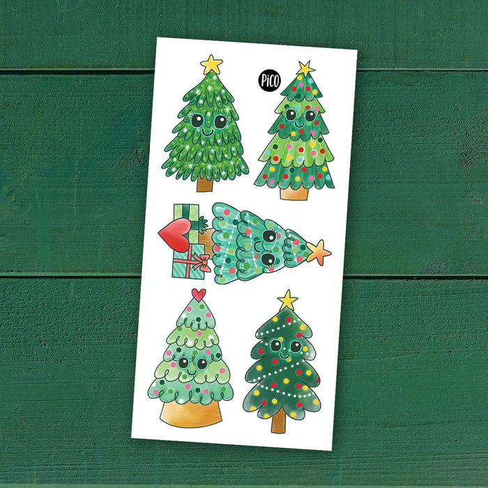 Sheet of Christmas tree tattoos with decorative elements on a green wooden background