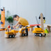 Wooden toy construction vehicles on a table with a child playing in the background.