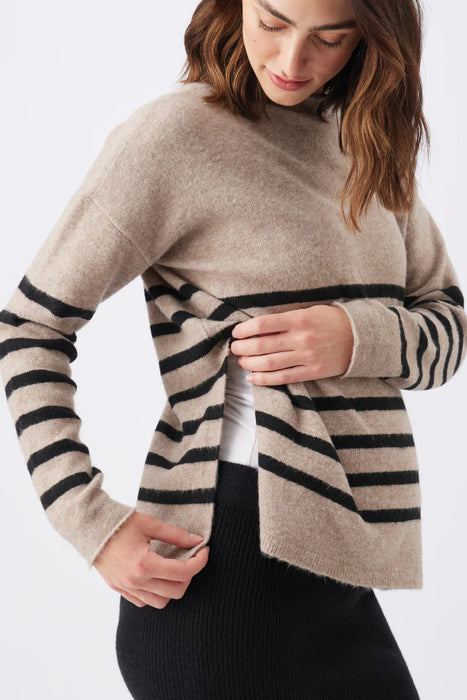 Woman wearing a beige sweater with black striped details on a white background