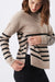 Woman wearing a beige sweater with black striped details on a white background