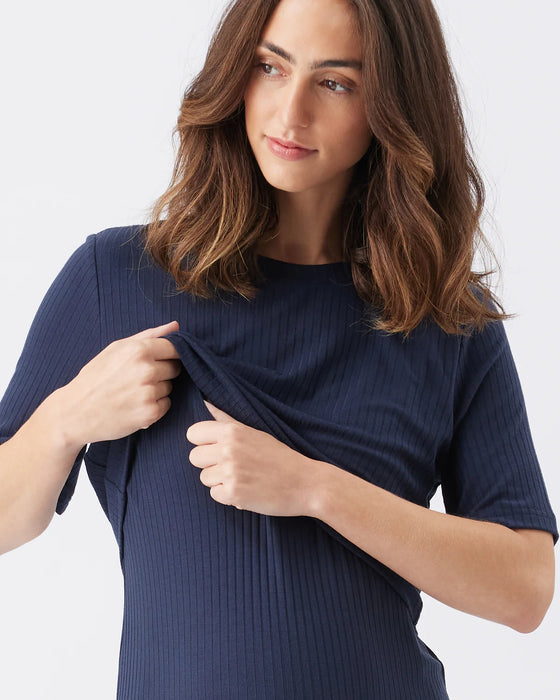 Woman wearing a navy blue ribbed dress against a white background