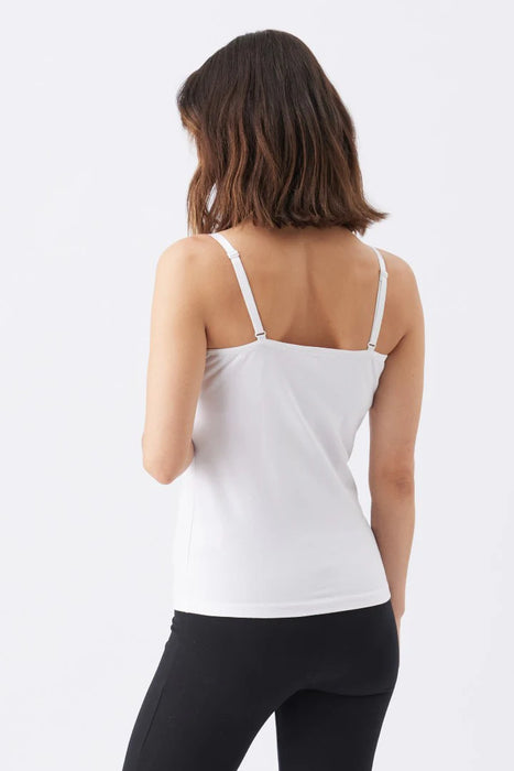 Woman wearing a white tank top and black leggings on a light gray background