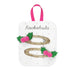 Two gold glitter hair clips decorated with green felt holly leaves and pink pom-poms, attached to a white display card with a pink ribbon loop and the brand name 'Rockahula'.