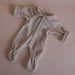 Beige baby doll onesie with a small logo on a pink background