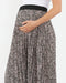woman holds her pregnant belly while wearing a floral skirt