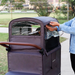 Person adjusting a wagon weather canopy with clear material in an outdoor setting