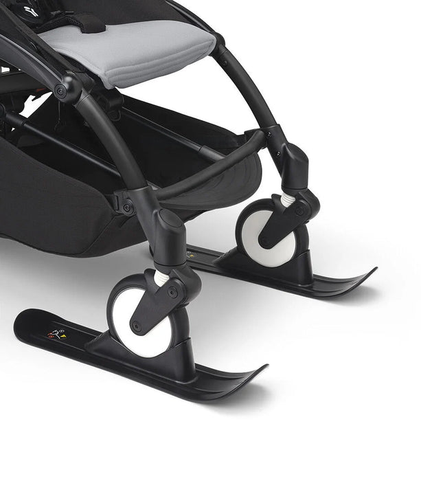 Black stroller with skis attached on a white background