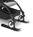 Black stroller with skis attached on a white background