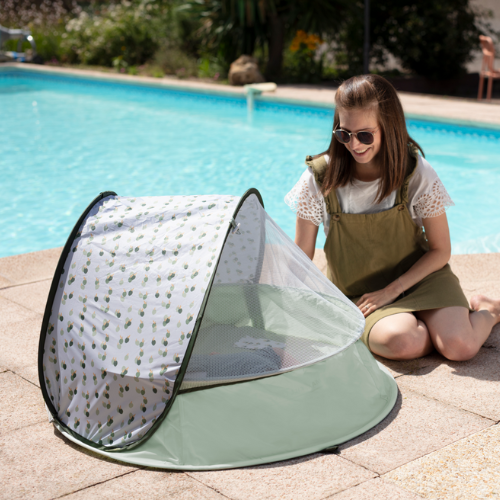 child rest in mosquito cover UV tent with caregiver close by