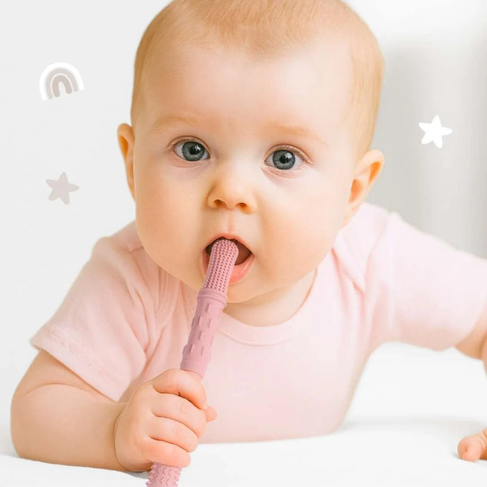 Baby holding a pink baby teething toy with a plain background