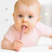 Baby holding a pink baby teething toy with a plain background