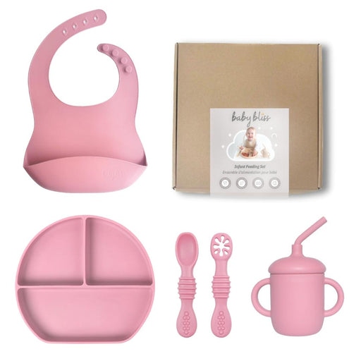 Pink baby feeding set with bib, plate, spoons, and cup on a white background