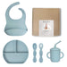 Baby feeding set with bib, plate, spoons, and cup on a white background