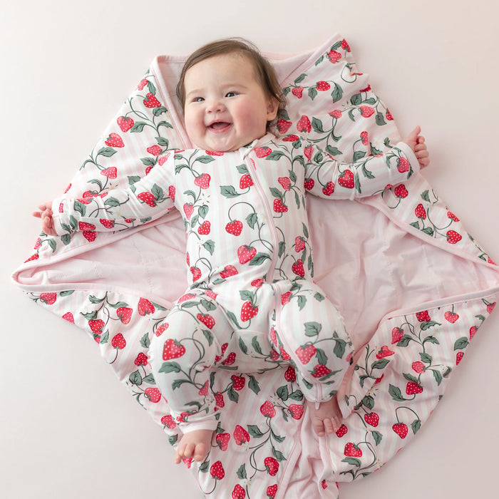 Baby lying on a pink blanket with strawberry pattern