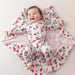Baby lying on a pink blanket with strawberry pattern