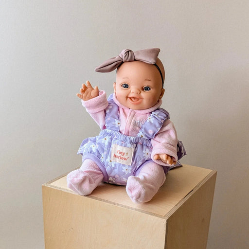 Baby doll in a pink outfit set in a purple baby doll carrier