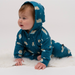 Baby wearing a blue onesie with animal patterns on a white background