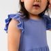 Child wearing a blue dress with ruffled sleeves against a white background