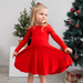 Young girl in a red twirl dress standing in front of decorated Christmas trees.