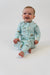 Baby wearing a light blue pajama set with vehicle prints on a white background