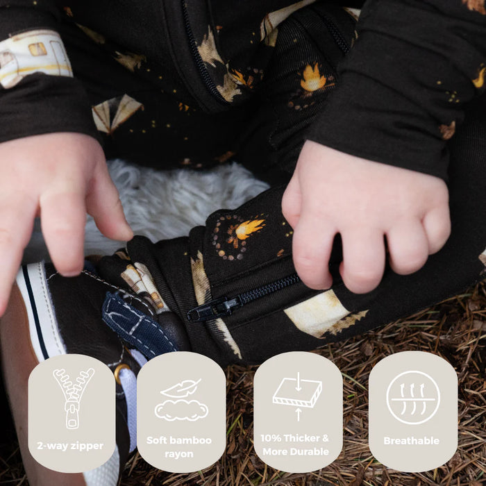 Child's hands on footless zippered romper with nature-themed design, surrounded by text icons indicating features of Belan J. bamboo