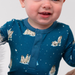 Child wearing a blue pajama with penguin design on a plain background