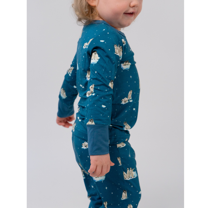 Child wearing a blue pajama set with animal print on a light gray background