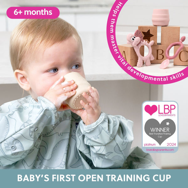 Baby drinking from a training cup with educational toys in the background, featuring LBP certification.