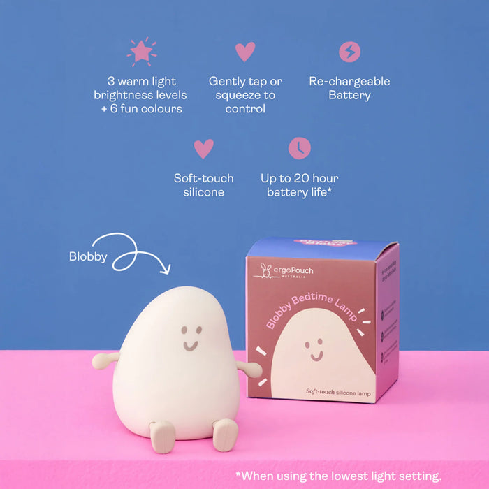 A soft, egg-shaped bedside lamp with a smiling face sits on a pink surface against a blue background, next to its branded retail box. Text callouts describe features such as warm light levels, touch control, rechargeable battery, and up to 20 hour battery life.