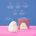 A soft, egg-shaped bedside lamp with a smiling face sits on a pink surface against a blue background, next to its branded retail box. Text callouts describe features such as warm light levels, touch control, rechargeable battery, and up to 20 hour battery life.