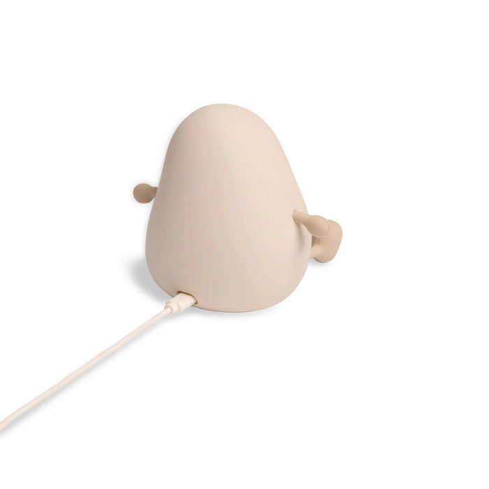 A minimalist night light in a beige color, featuring a power cord plug extending from the bottom, shown against a solid white background.