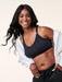 Woman wearing a black nursing sports bra and black pants on a beige background